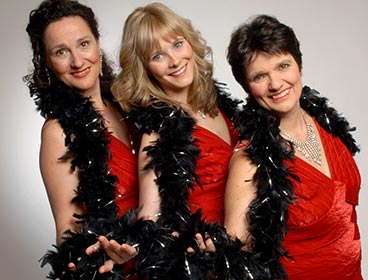 Drei Sängerinnen im roten Kleid in Revuepose